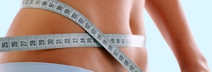 Close up of a slim waist with measuring tape.